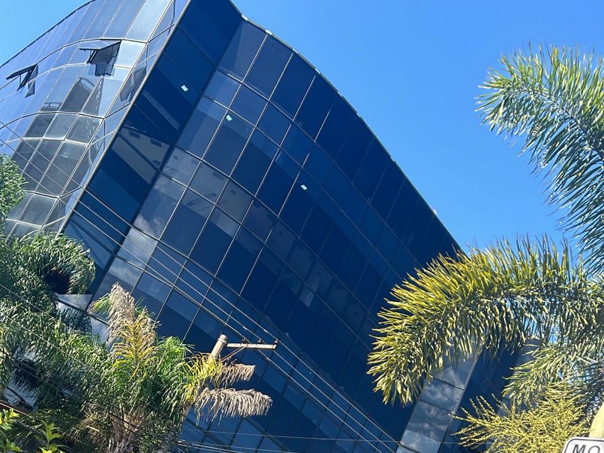 Edifício da DFM Odontologia na Av. Goiás, com fachada de vidros azul-marinho e palmeiras.